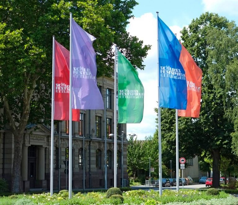 Mehrere Werbefahnen in unterschiedlichen Farben am Mast.