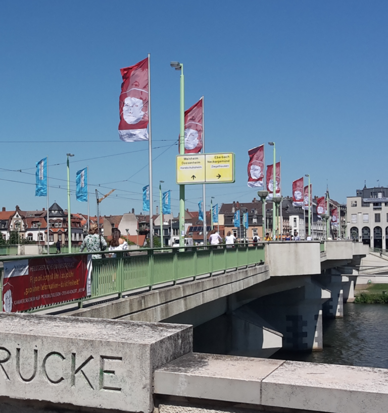 Mehrere individuell bedruckte Werbefahnen wehen an einer Brücke