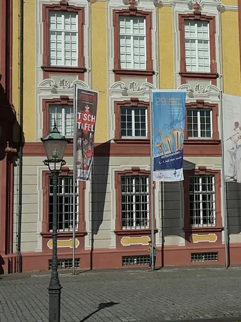 Zwei unterschiedlich bedruckte Werbefahnen vor einem Schloss