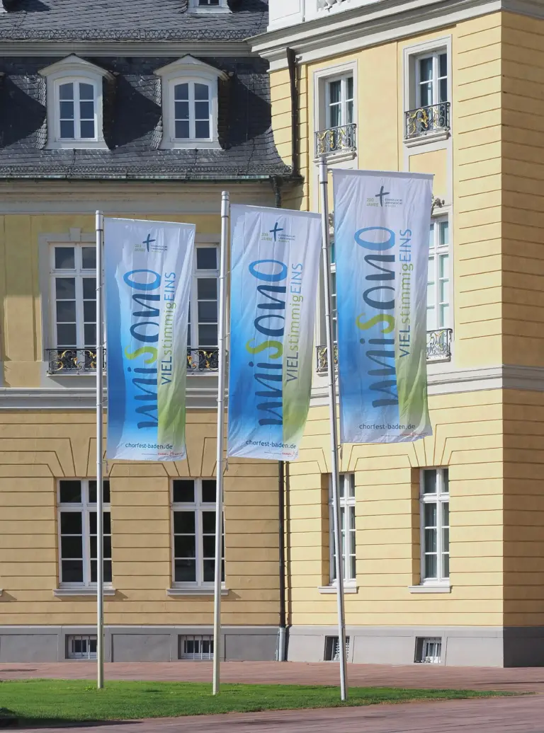 Bedruckte Werbefahnen wehen vor Schloss.
